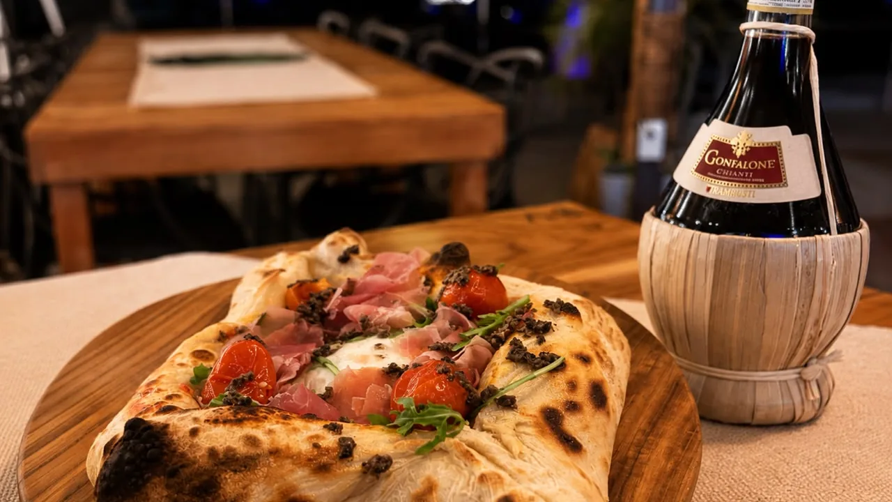 Pizza con jamón serrano y rúcula junto a una botella de vino italiano